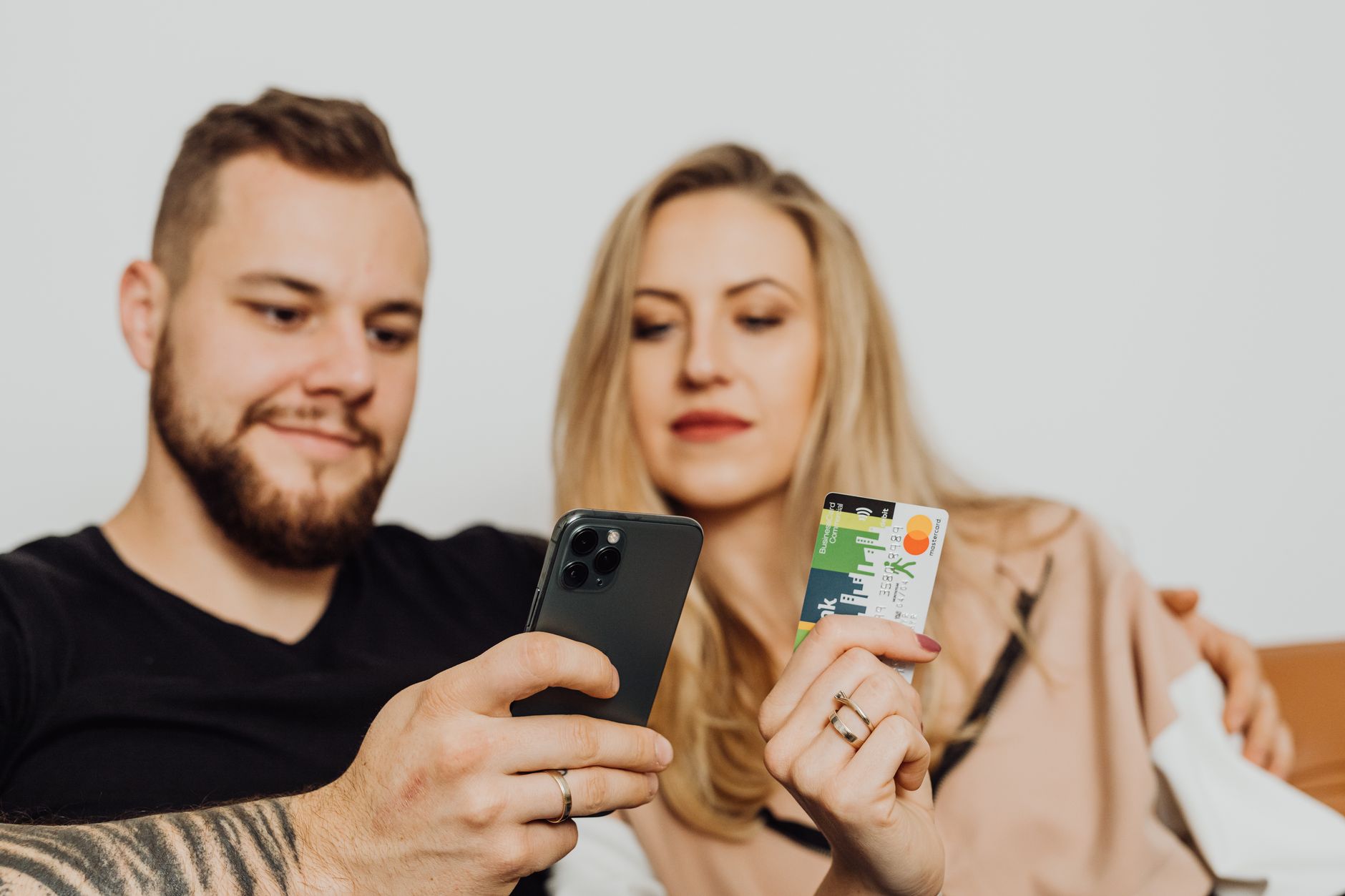 Mężczyzna i kobieta siedzą blisko siebie i razem patrzą na ekran smartfona